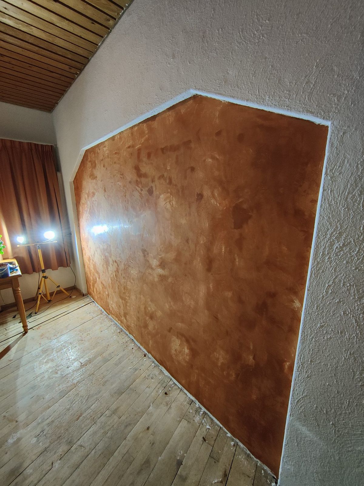 Roestkleurige leemwand in een zeshoekige nis onder een schuin dak