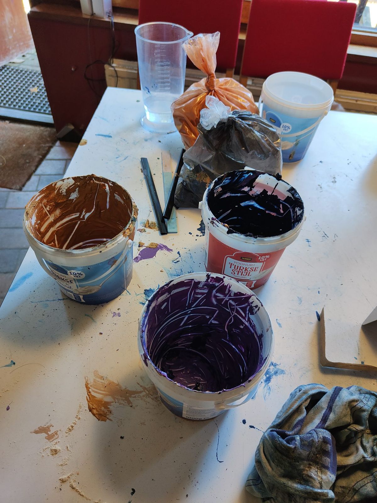 Emmers met aangemaakt pigment in oker, blauw en violet op de werktafel